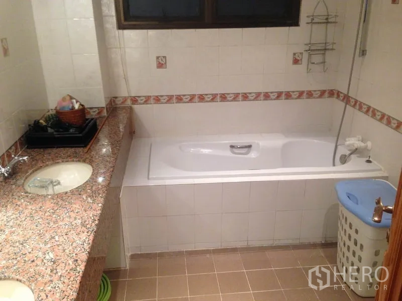 Condominium for rent in Bang Rak, Bangkok - Bathroom with built-in bathtub and long granite countertop with under-mount sink.