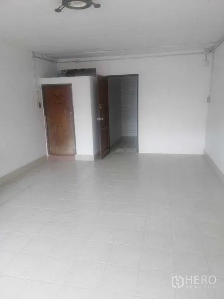 Shophouse for rent in Khlong Toei, Bangkok - Open room with tile floor, wooden storage cabinet and doorway to washroom.