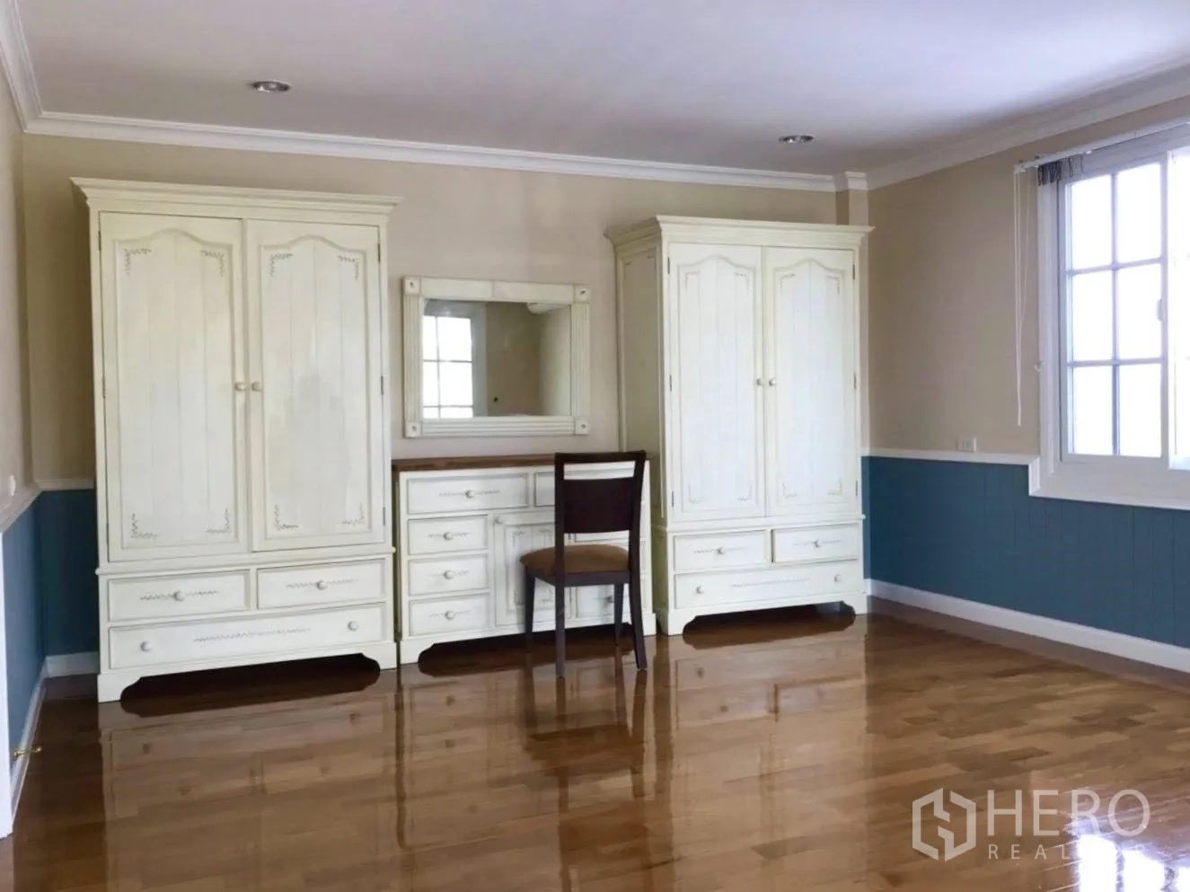 Detached House for rent in Mueang Samut Prakan, Samut Prakan - Bedroom with cream wardrobes, dressing table and polished wood floor.