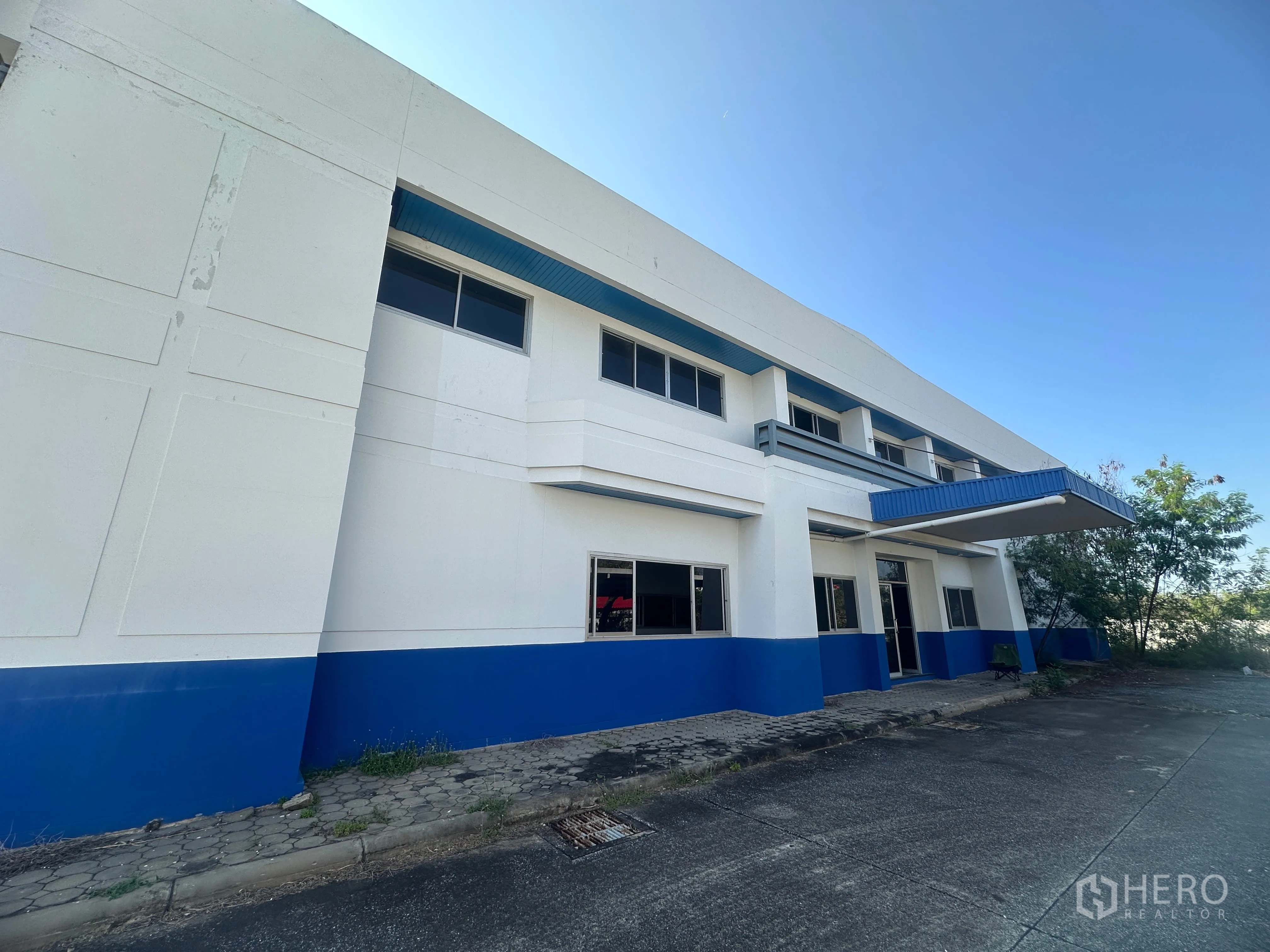 โรงงาน for rent in Bang Pa-in, Phra Nakhon Si Ayutthaya - ด้านหน้าตัวอาคารพร้อมแถบสีน้ำเงินและหลังคาทางเข้า