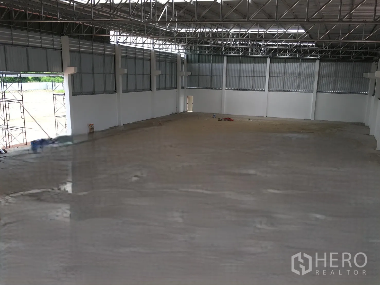 仓库 for sale in Sai Noi, Nonthaburi - 仓库内部开放空间，混凝土地面、钢桁架屋顶和宽大装卸门。