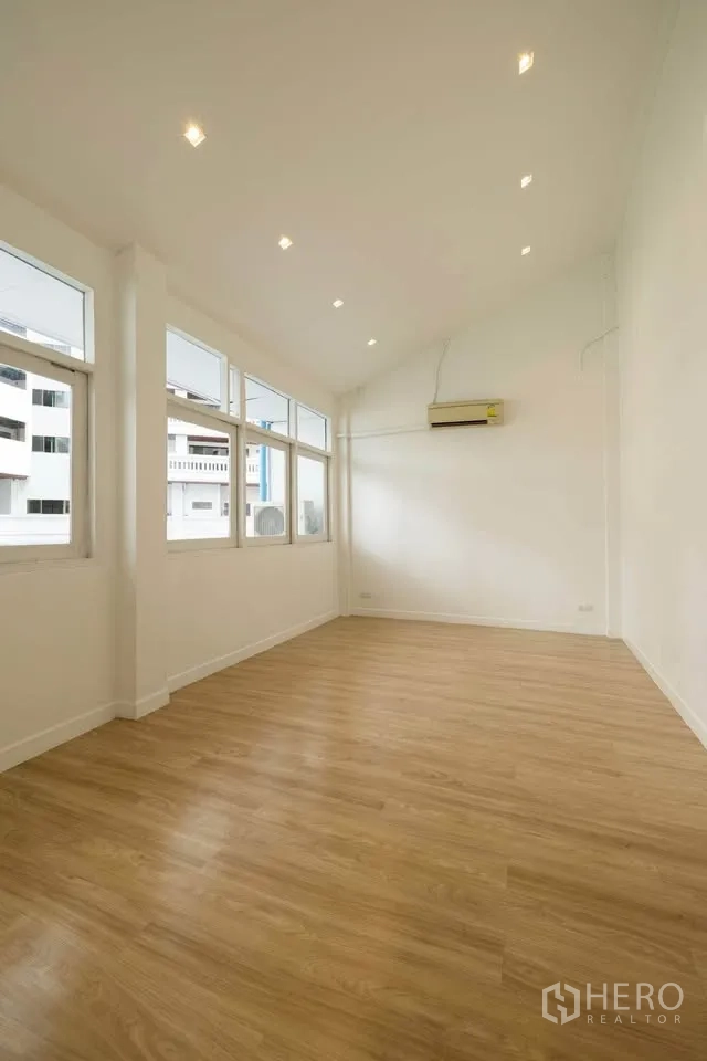 联排别墅 出租在Khlong Toei, Bangkok - 楼上宽敞房间，挑高天花与筒灯，多扇窗户引入自然采光。