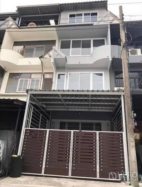 Home Office for rent or sale in Watthana, Bangkok - Four-storey townhouse facade with gated carport and curved balconies in an urban row.