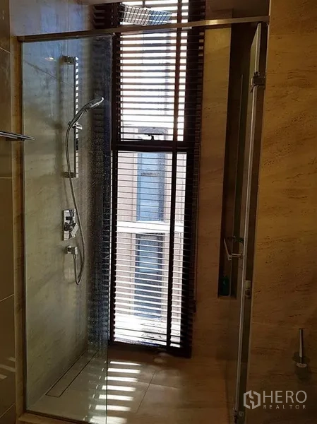 Condominium for rent in Watthana, Bangkok - Bathroom with glass shower enclosure and window blinds.