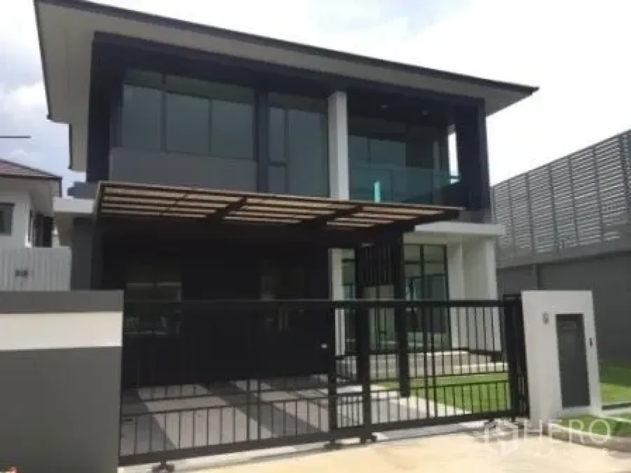 Detached House for rent in Bang Kapi, Bangkok - Modern two-storey detached house facade with glass balcony, gated driveway and covered carport.