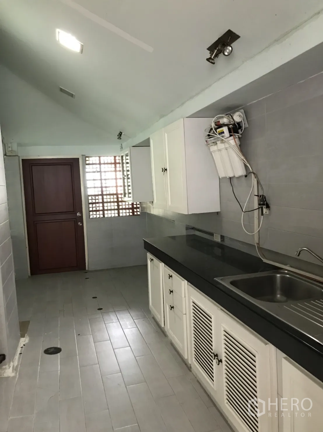 บ้าน ให้เช่าในLat Krabang, Bangkok - ครัวแบบแกลเลย์ ตู้สีขาว เคาน์เตอร์ท็อปสีดำ อ่างล้างจานสแตนเลส ผนังกระเบื้องสีเทา