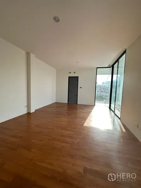 独立式住宅 出租在Watthana, Bangkok - 采光充足的房间，木地板，落地推拉门通向带城市景观的阳台。