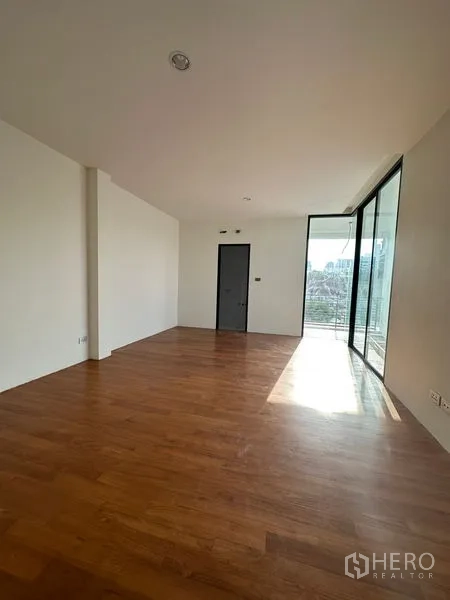 独立式住宅 出租在Watthana, Bangkok - 采光充足的房间，木地板，落地推拉门通向带城市景观的阳台。