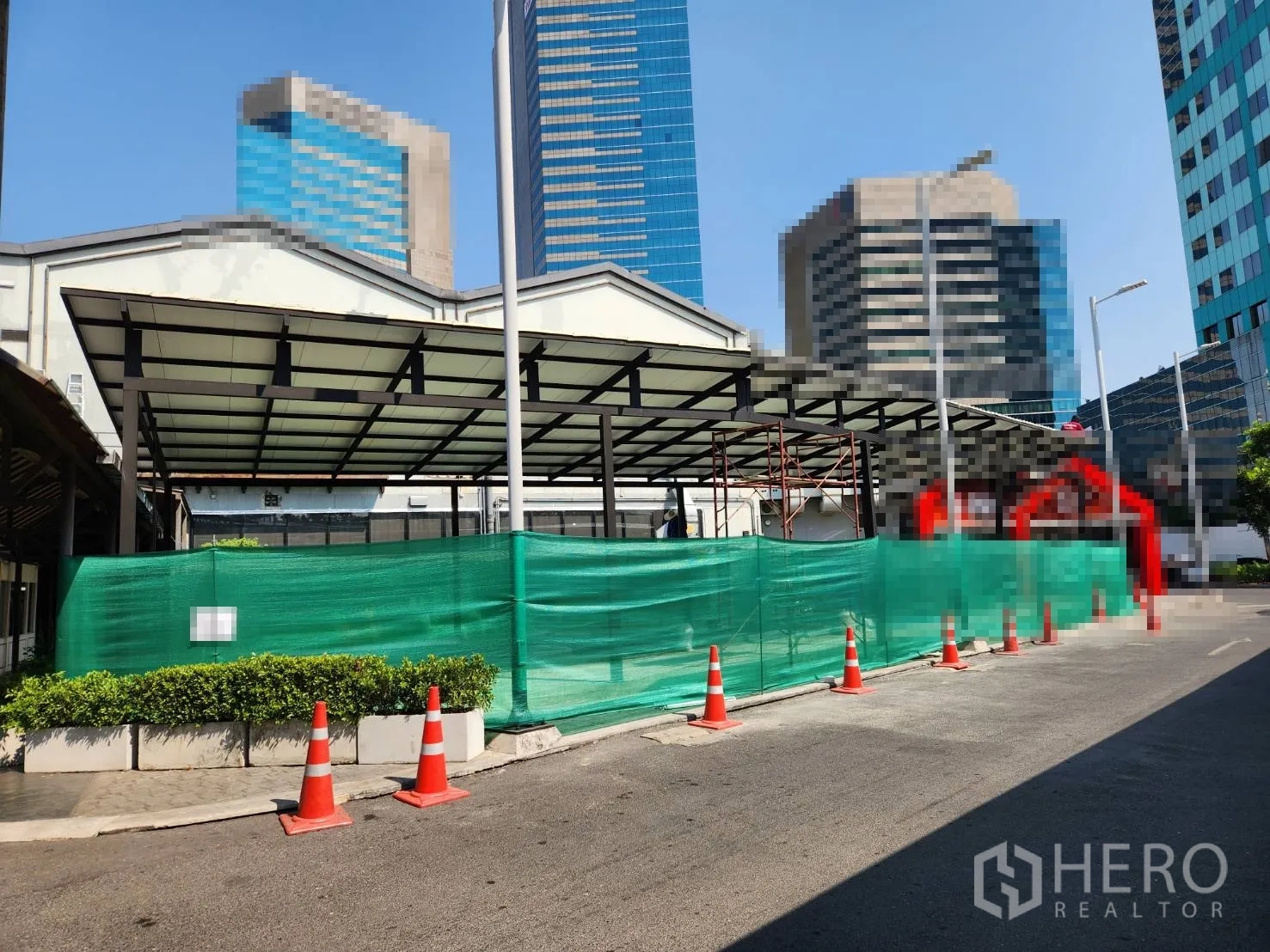 零售空间 出租在Khlong Toei, Bangkok - 临街商铺雨棚，设绿色围挡与路锥，背景为高楼，靠近BTS Thonglor站。