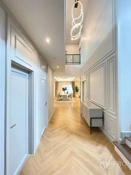 Detached House for rent in Bang Phli, Samut Prakan - Double-height hallway with herringbone floors, wall mouldings and statement lighting.