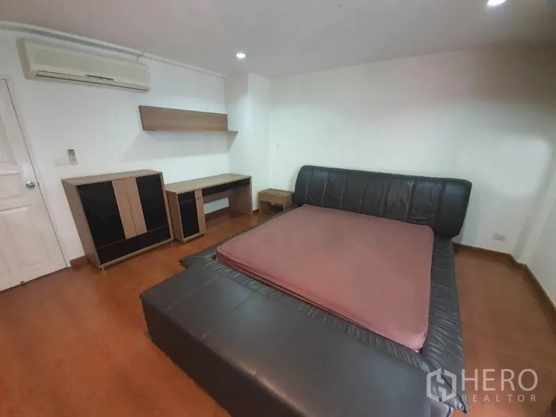 Townhouse for rent in Phaya Thai, Bangkok - Bedroom with black leather platform bed, wooden floors, split A/C, work desk and shelving.