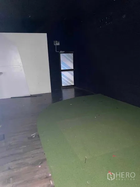 อาคารพาณิชย์ ให้เช่าในHuai Khwang, Bangkok - พื้นที่ค้าปลีกบรรยากาศมืด ผนังสีเข้ม มีหน้าต่างเล็กและพื้นหญ้าเทียมบางส่วน