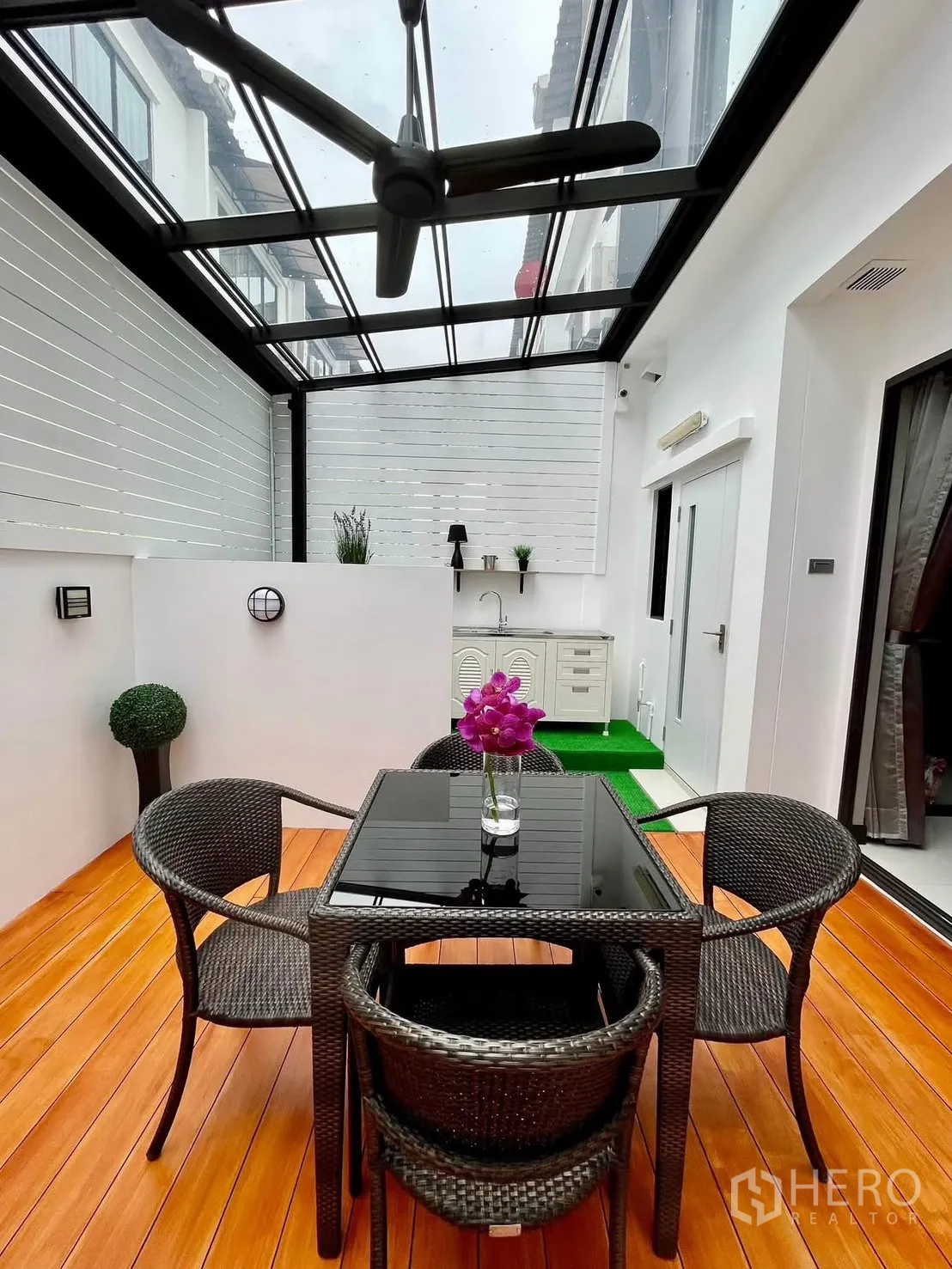 Townhouse for rent in Lat Phrao, Bangkok - Outdoor dining area under glass roof with table, chairs and pantry.