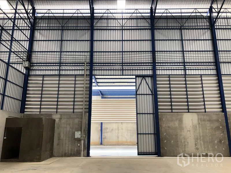 Warehouse for rent in Lat Lum Kaeo, Pathum Thani - Tall sliding entrance door and steel frame structure of the warehouse with ventilation panels.
