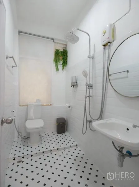 Townhouse for rent in Khlong Toei, Bangkok - Modern bathroom with rain shower, vanity basin, toilet and patterned floor tiles.