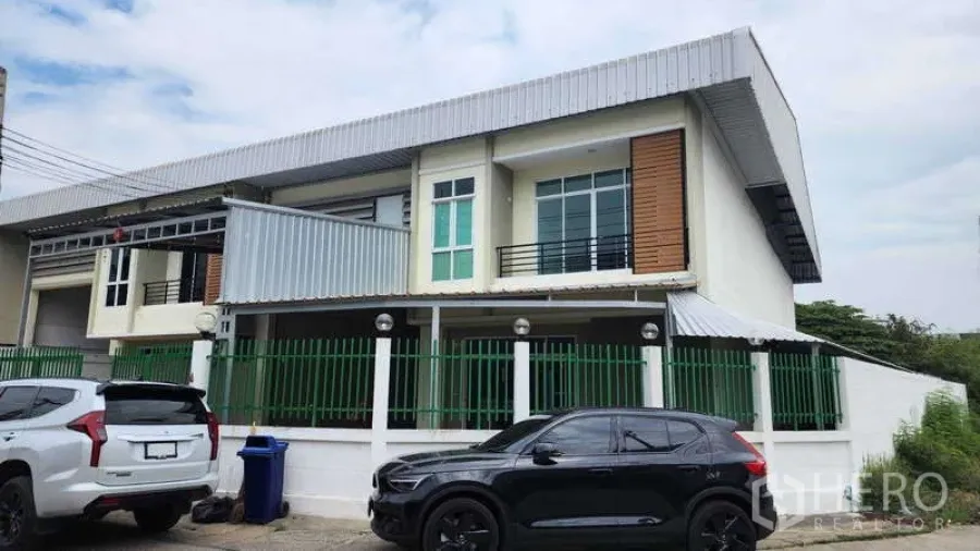 Factory for rent in Samut Sakhon - Angled exterior view of corner factory with green fence and canopies.