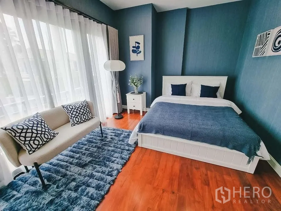 Detached House for rent or sale in Bang Phli, Samut Prakan - Blue-themed bedroom with bed, loveseat, and sheer curtains across wide windows.