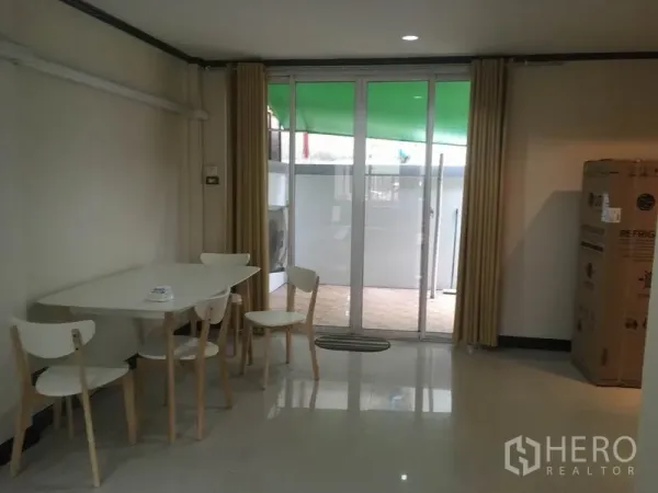 Townhouse for rent in Din Daeng, Bangkok - Dining corner with white table and chairs opening to a patio through glass doors.