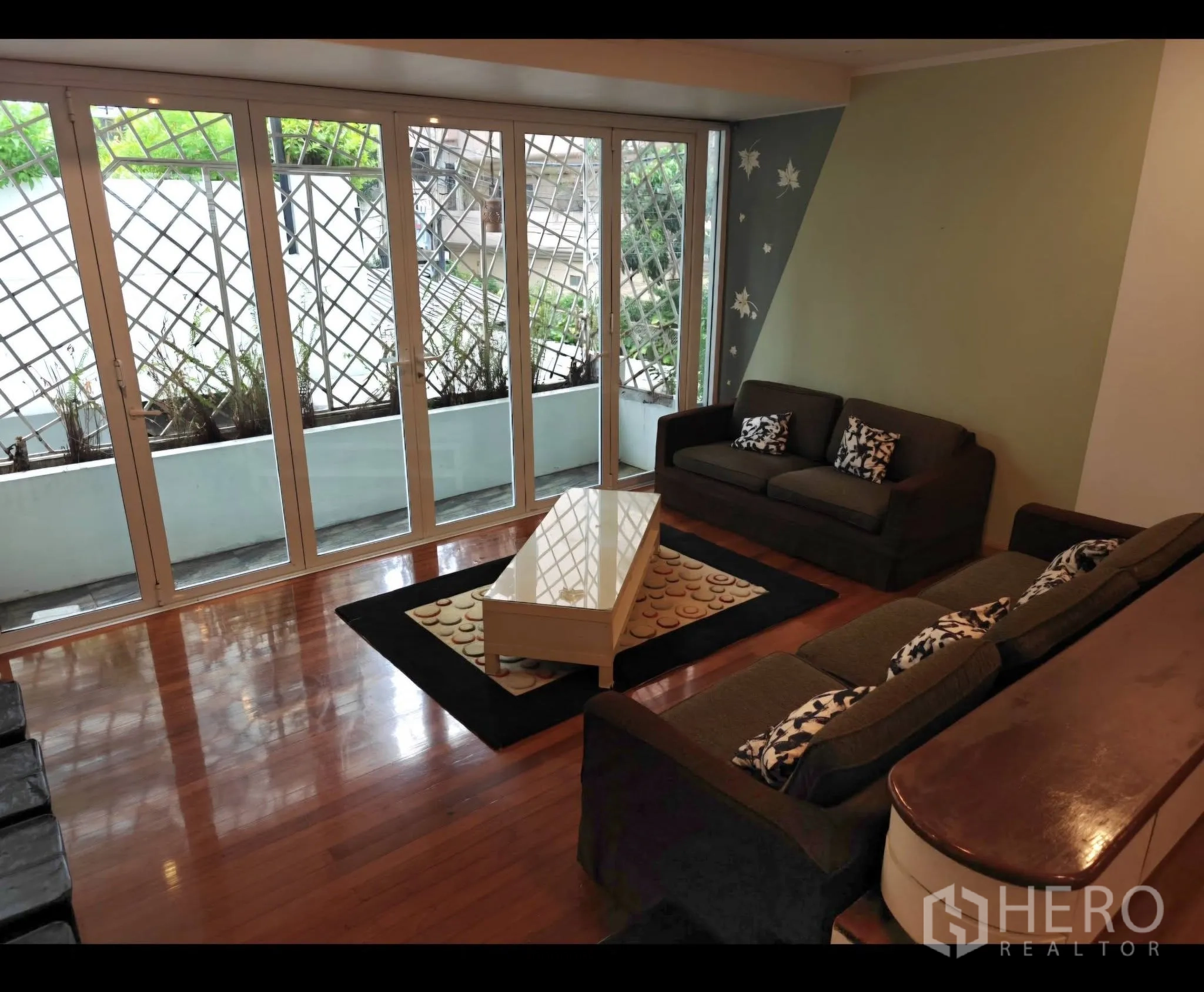 Condominium for rent in Sathon, Bangkok - Second lounge opening to a long balcony with planters and lattice, featuring two sofas and a coffee table.