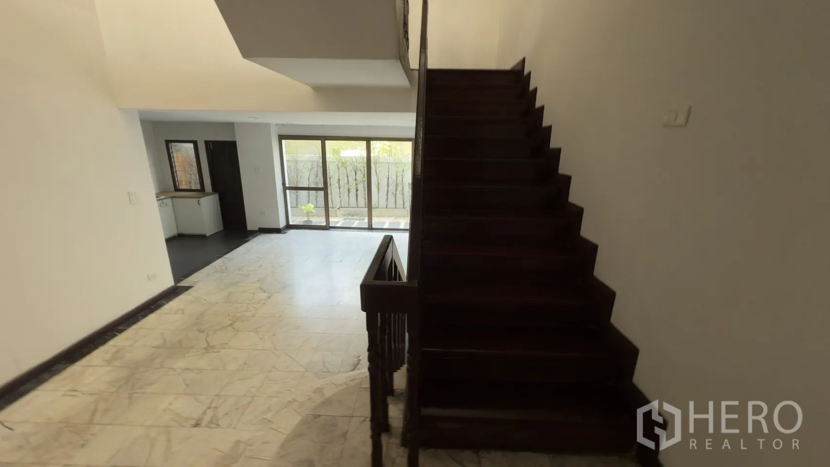 ทาวน์เฮาส์ for rent in Watthana, Bangkok - ห้องนั่งเล่นชั้นล่างพื้นหินอ่อน พร้อมบันไดไม้และประตูกระจกมองสู่สวน