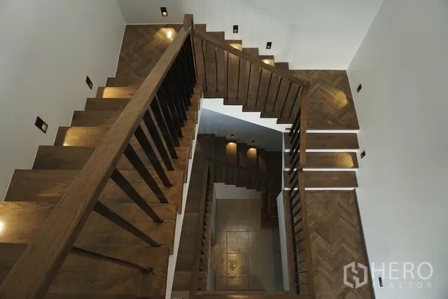 Detached House for rent in Watthana, Bangkok - Wooden staircase with modern step lighting and white walls.