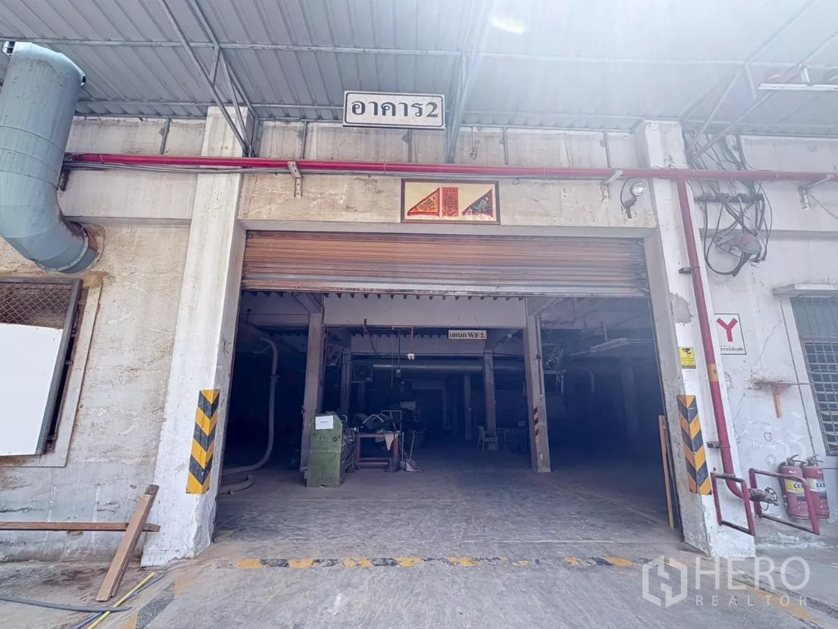 工厂 出租或出售在Bang Khun Thian, Bangkok - 工厂入口特写，金属卷闸门、警示标识与雨棚。