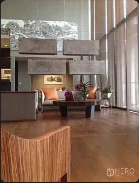 公寓 出租在Sathon, Bangkok - 优雅挑高客厅，沙发与茶几对着高大的玻璃窗。