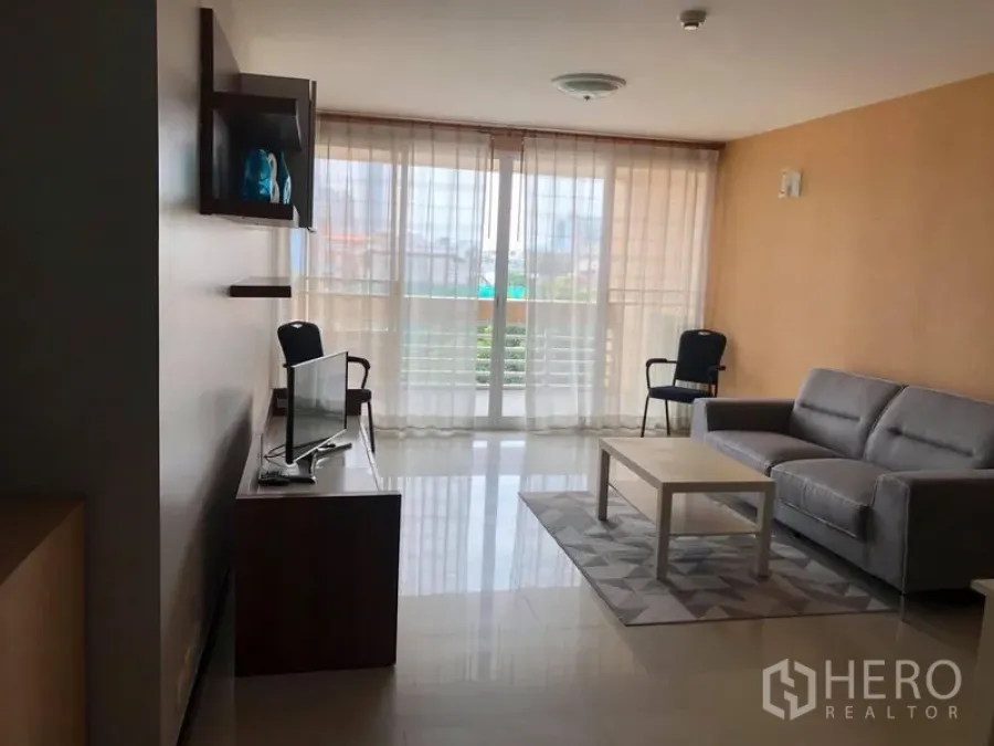 คอนโด ขายในWatthana, Bangkok - ห้องนั่งเล่นพร้อมโซฟาสีเทา โต๊ะกลาง ชั้นวางทีวี และหน้าต่างเต็มบานพร้อมผ้าม่านโปร่ง