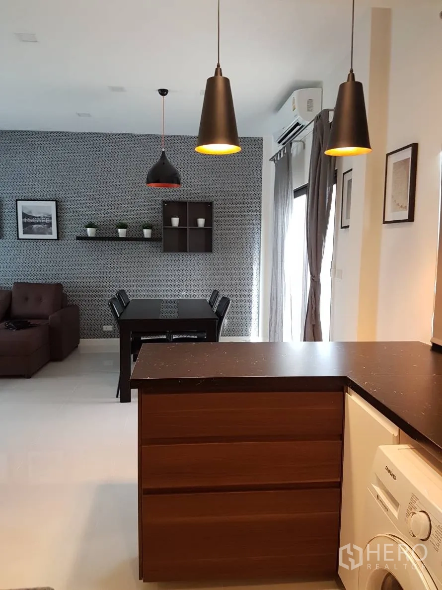 Townhouse for rent or sale in Saphan Sung, Bangkok - Open-plan dining and living area with pendant lights, dining table, sofa and balcony curtains.