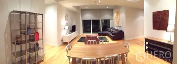 Condominium for rent in Ratchathewi, Bangkok - Open-plan living and dining room with wood floors, gray sofa, TV console and large windows overlooking the city.