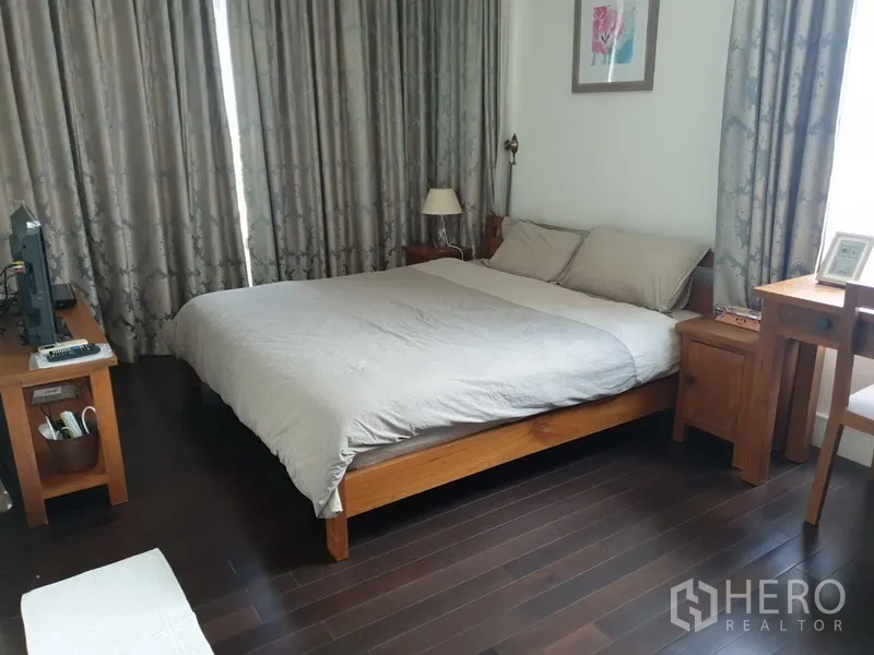 คอนโด ให้เช่าหรือขายในKhlong Toei, Bangkok - ห้องนอนใหญ่เตียงขนาดใหญ่ โต๊ะข้างเตียงไม้ พื้นไม้เข้ม และผ้าม่านยาว.