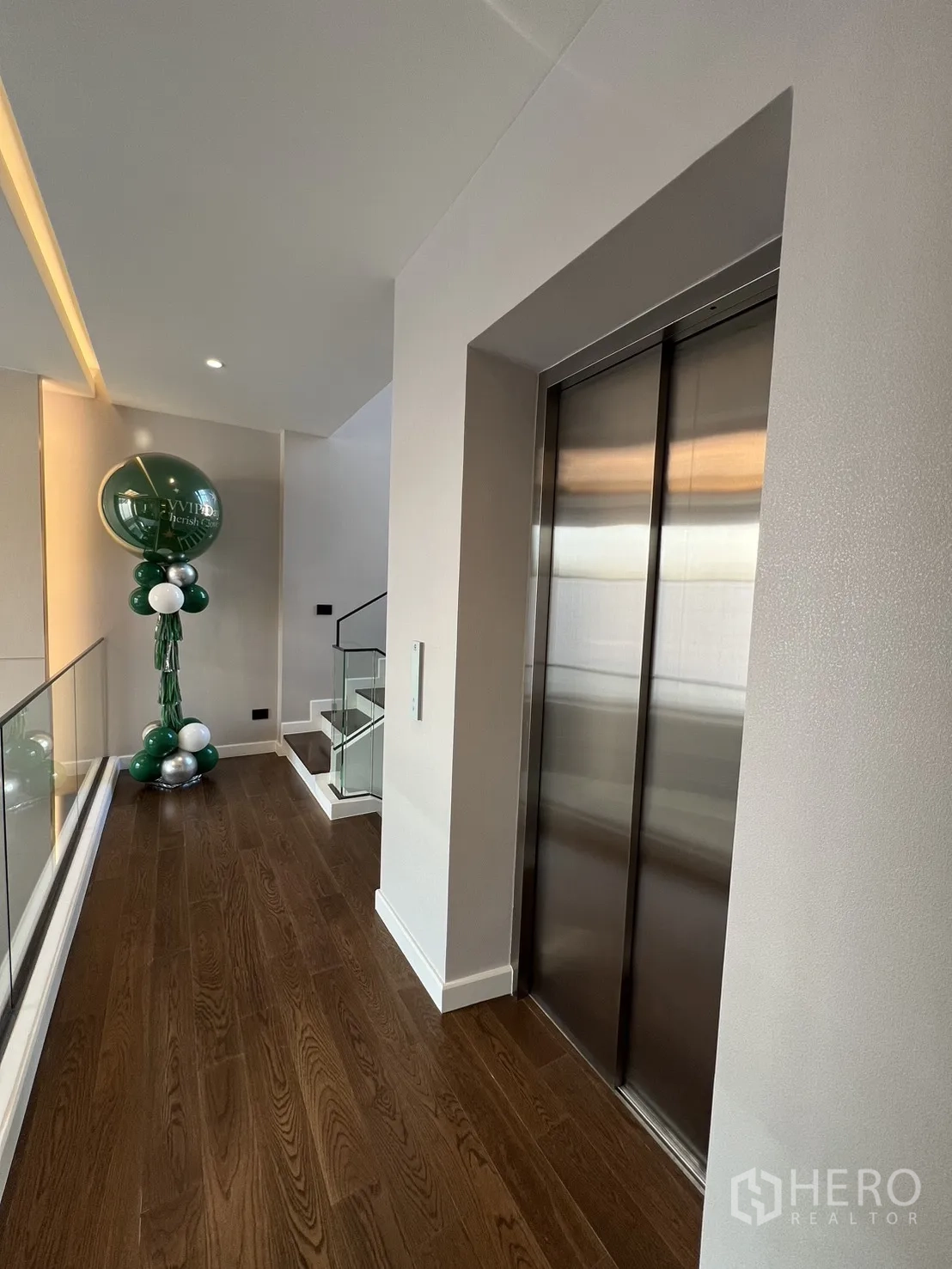 บ้าน ขายในLat Phrao, Bangkok - โถงชั้นบนพร้อมลิฟต์ในบ้านและราวบันไดกระจก พื้นไม้