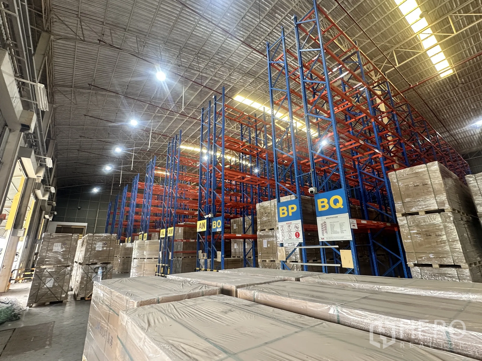 Warehouse for rent in Lat Krabang, Bangkok - Warehouse hall with tall racking rows and stacked pallets under bright lighting.