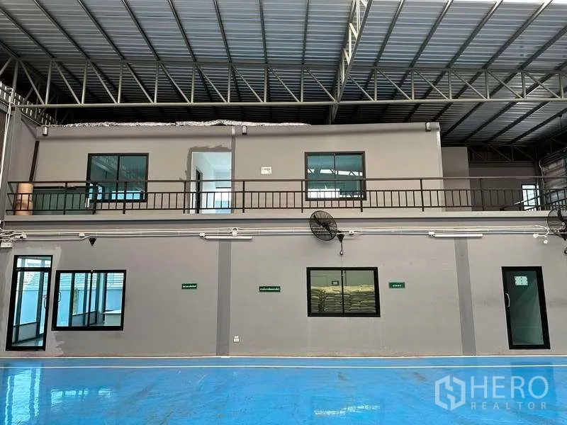 Factory for rent in Samut Prakan - Warehouse interior with blue epoxy floor, mezzanine offices and steel roof truss.
