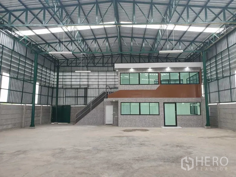 Warehouse for rent in Prawet, Bangkok - Spacious warehouse interior with steel roof trusses and a two-storey glass-front office.