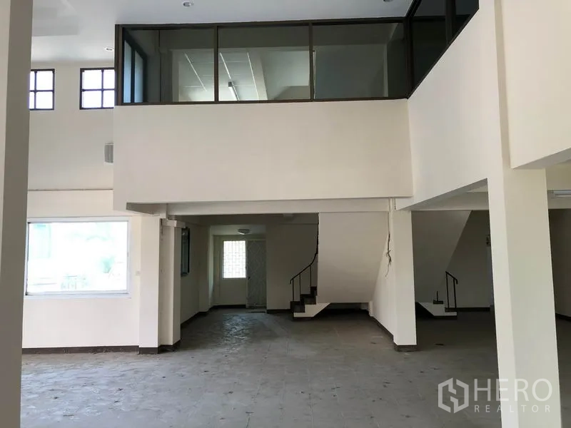 Shophouse for sale in Lam Luk Ka, Pathum Thani - Open retail hall with central columns and stairs leading to the upper mezzanine level.
