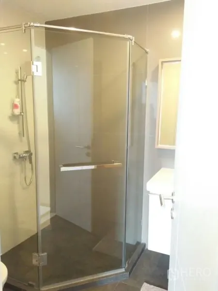 Condominium for rent in Huai Khwang, Bangkok - Modern bathroom featuring a glass-enclosed corner shower and handheld spray.