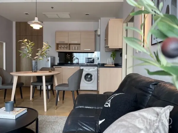 คอนโด ให้เช่าในWatthana, Bangkok - ห้องนั่งเล่นหันเข้าหาครัวขนาดกะทัดรัดพร้อมเครื่องซักผ้าและท็อปหินสีดำ