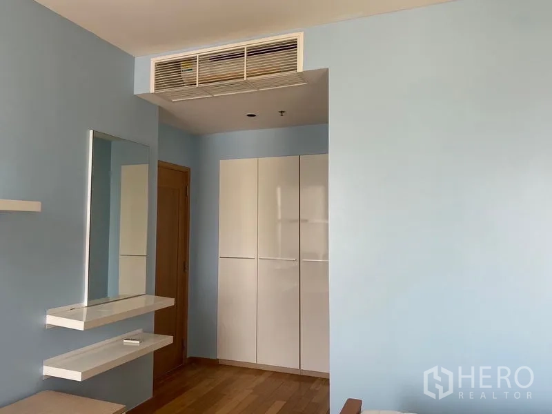 คอนโด ให้เช่า - มุมห้องนอนผนังสีฟ้า ตู้เสื้อผ้าบิลท์อิน ชั้นลอย และช่องแอร์ฝ้า