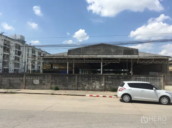 คลังสินค้า ให้เช่าในKhlong Luang, Pathum Thani - ด้านหน้าโกดังติดถนน มีกำแพงรั้วและประตูทางเข้า เหมาะสำหรับรถบรรทุกเข้าออก เขตคลองหลวง