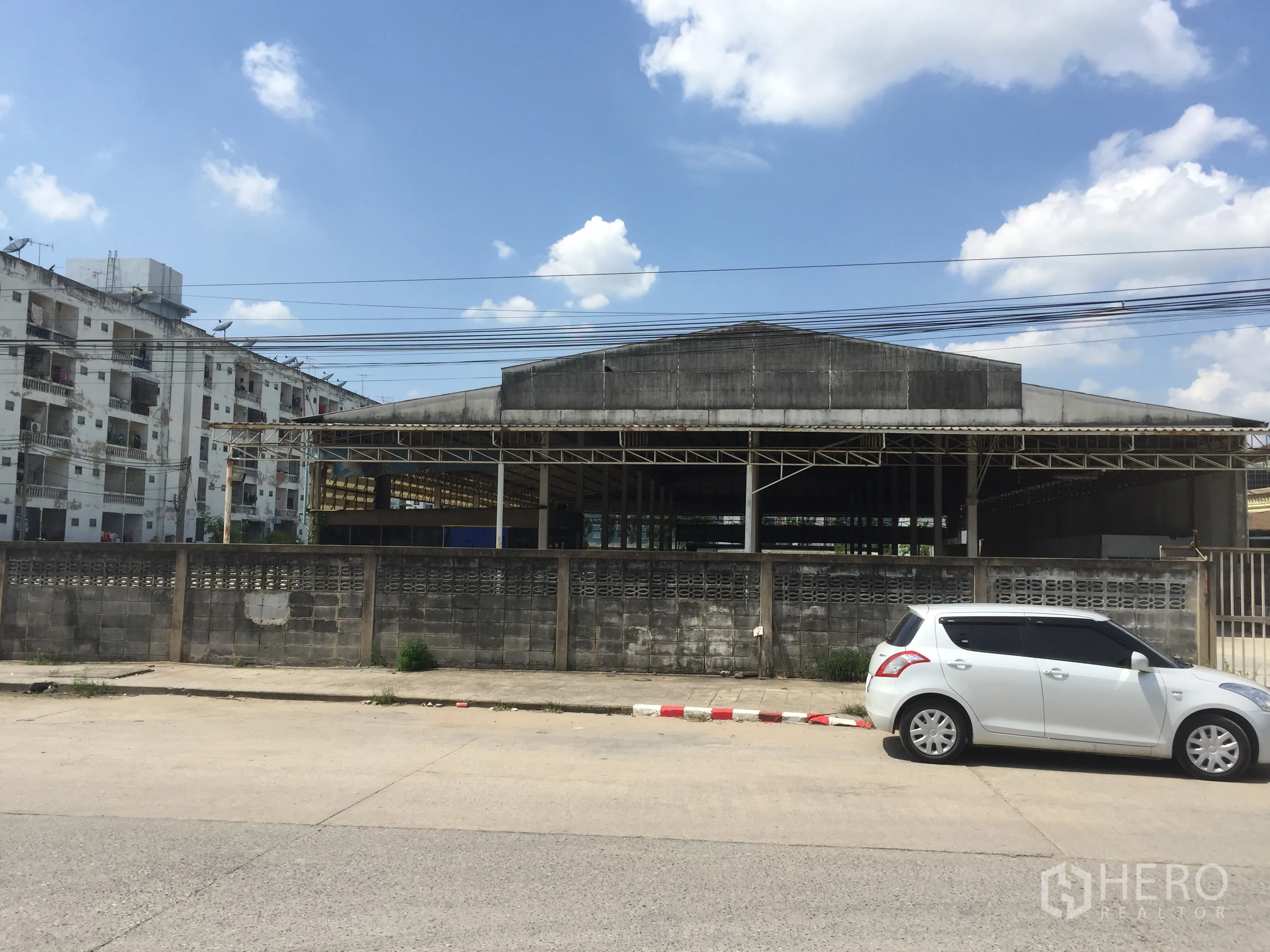 คลังสินค้า ให้เช่าในKhlong Luang, Pathum Thani - ด้านหน้าโกดังติดถนน มีกำแพงรั้วและประตูทางเข้า เหมาะสำหรับรถบรรทุกเข้าออก เขตคลองหลวง
