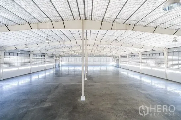 Warehouse for rent in Phra Nakhon Si Ayutthaya - Spacious warehouse interior with high steel roof, hanging lights, ventilation louvres and polished concrete floor.