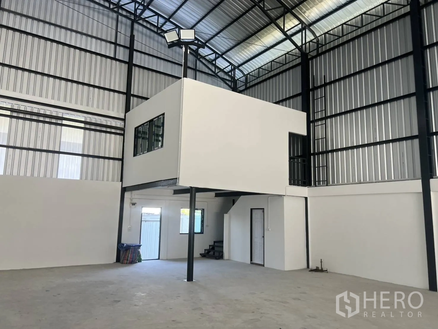 Warehouse for rent in Bang Phli, Samut Prakan - Warehouse interior corner with elevated office, doors, and tall metal cladding walls.