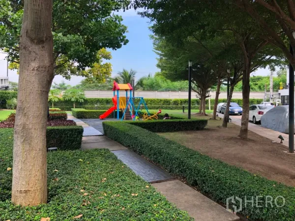 Townhouse for sale in Bang Kapi, Bangkok - Leafy communal garden with paved walkways and a colorful children’s playground beside parking.