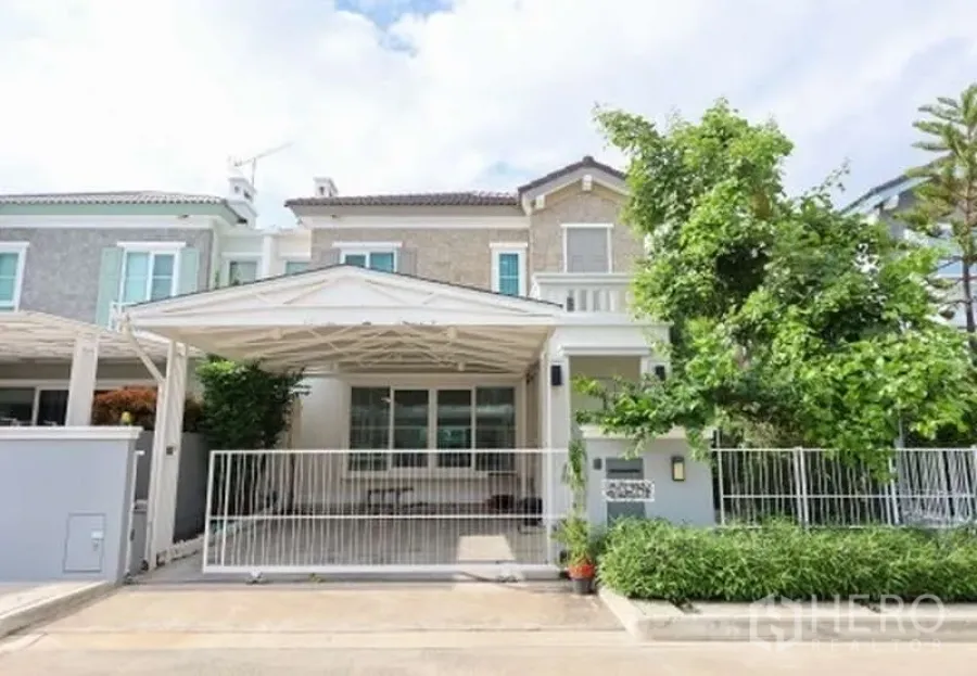 Detached House for rent or sale in Prawet, Bangkok - Front façade of the detached house with gate, carport and mature tree.