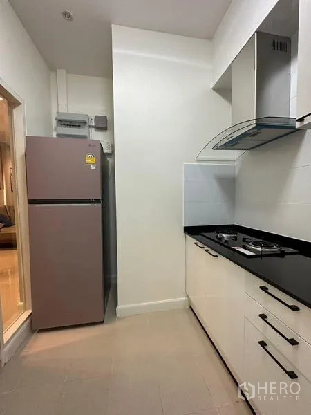 Townhouse for rent in Chom Thong, Bangkok - Western kitchen nook with refrigerator, gas hob and range hood.