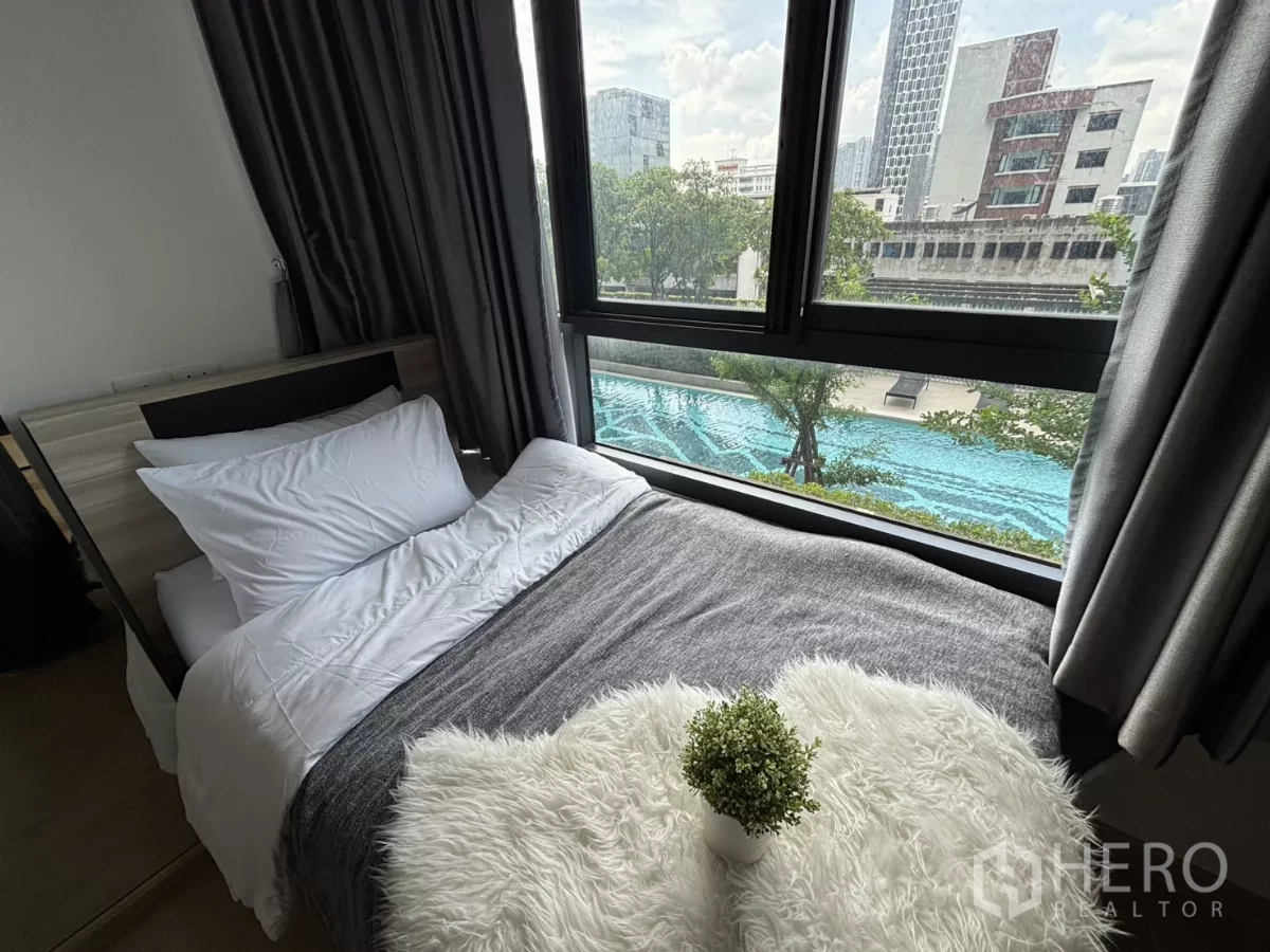 Condominium for rent in Phra Khanong, Bangkok - Corner bed placed by panoramic windows with pool views below.