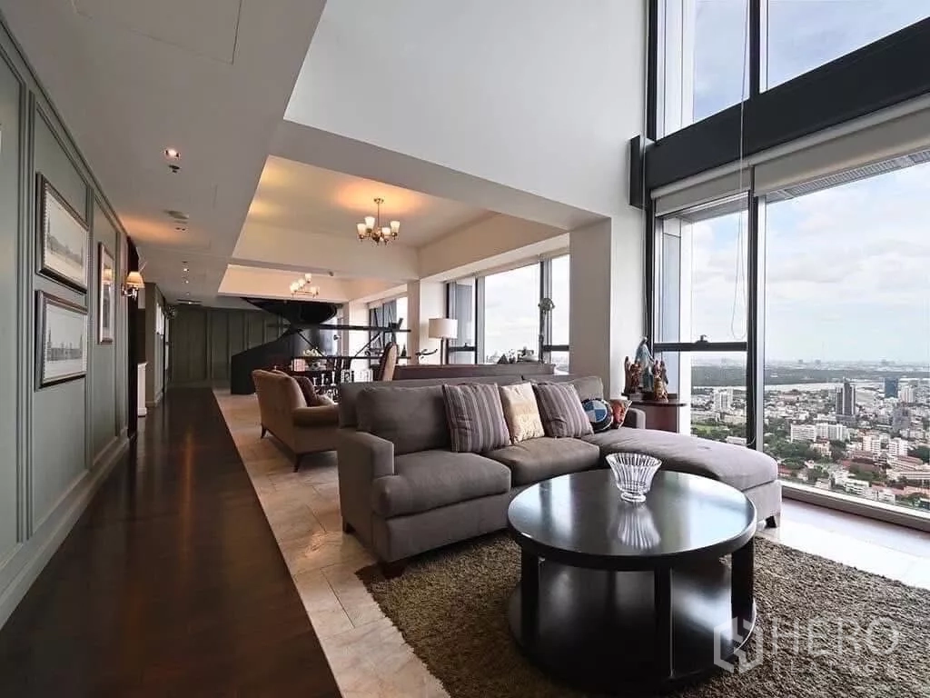 Condominium for rent in Sathon, Bangkok - Expansive living area with dark wood floors, round coffee table and sweeping skyline view.