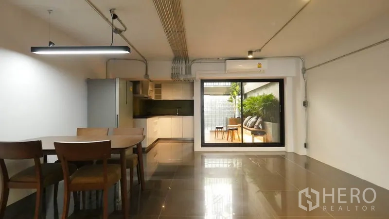 Townhouse for rent in Khlong Toei, Bangkok - Dining area and modern kitchen with sliding window looking to a green courtyard.