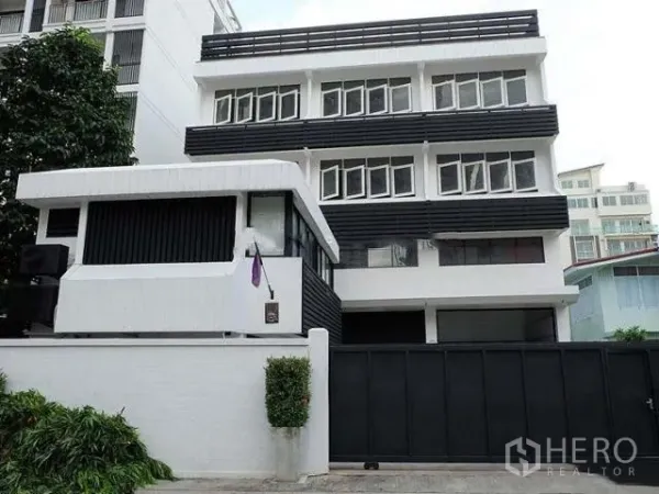 สำนักงานที่บ้าน ขายในKhlong Toei, Bangkok - ภาพด้านหน้าอาคารโฮมออฟฟิศ 4 ชั้น โทนขาวดำ พร้อมประตูรั้วเลื่อน